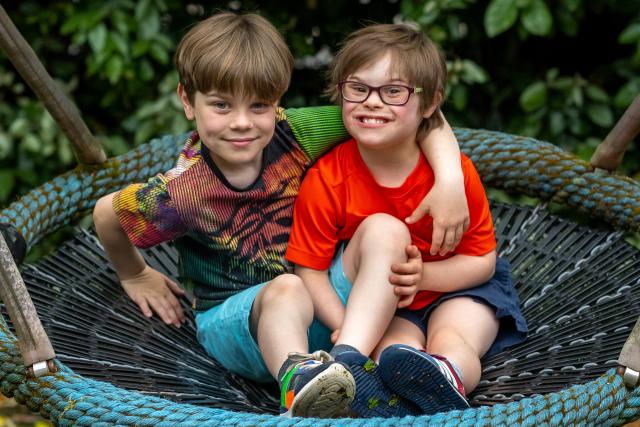 Two children sitting on an outdoor hanging chair