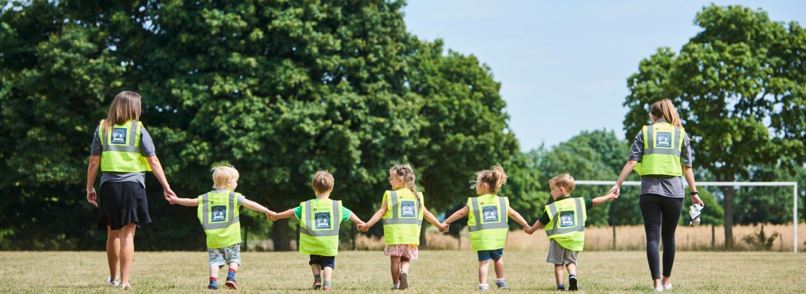 Children walking hand-in-hand in a field. Banner.