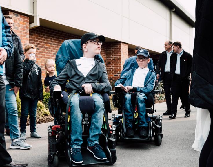 Two boys in powered wheelchairs.